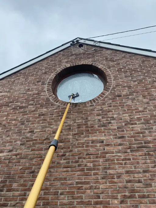 Nettoyage d'une vitre en hauteur à la perche